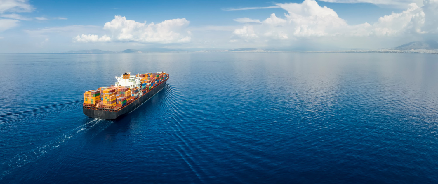 Panoramic aerial view of a industrial cargo container ship traveling over calm, open sea with copy space